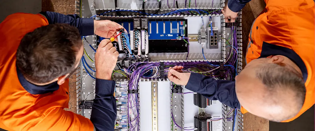 Electricians connecting structured cabling and labelled wires inside a communications or security panel