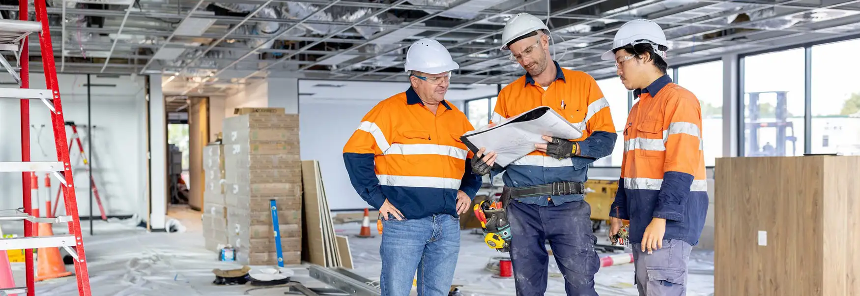 Three Electricians discussing plans during commercial electrical installation on a construction site